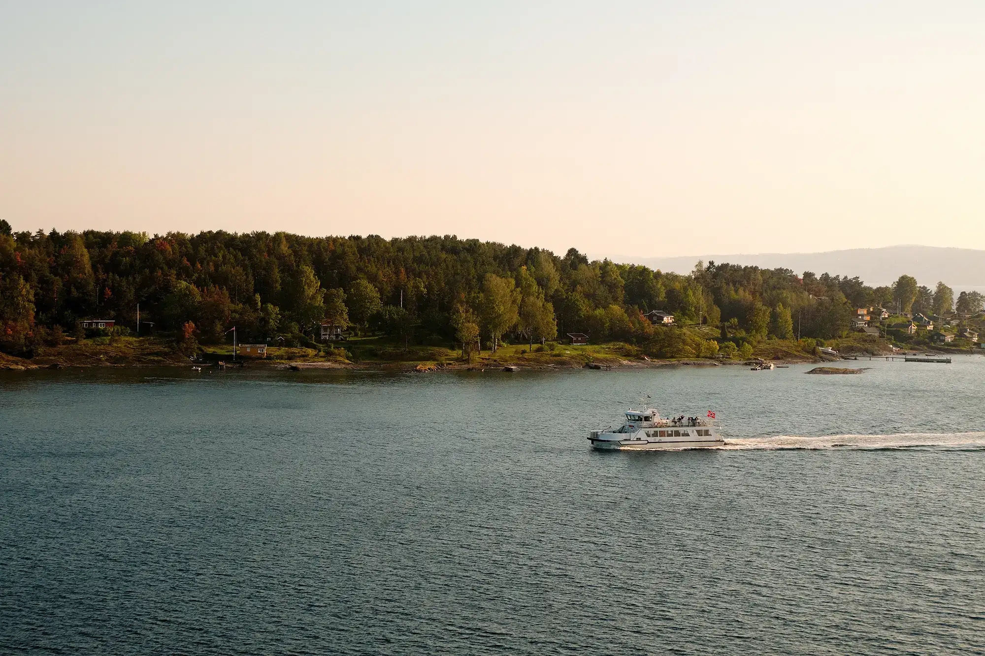 Fähre fährt auf dem Meer nahe einer bewaldeten Küste bei Oslo in Norwegen.