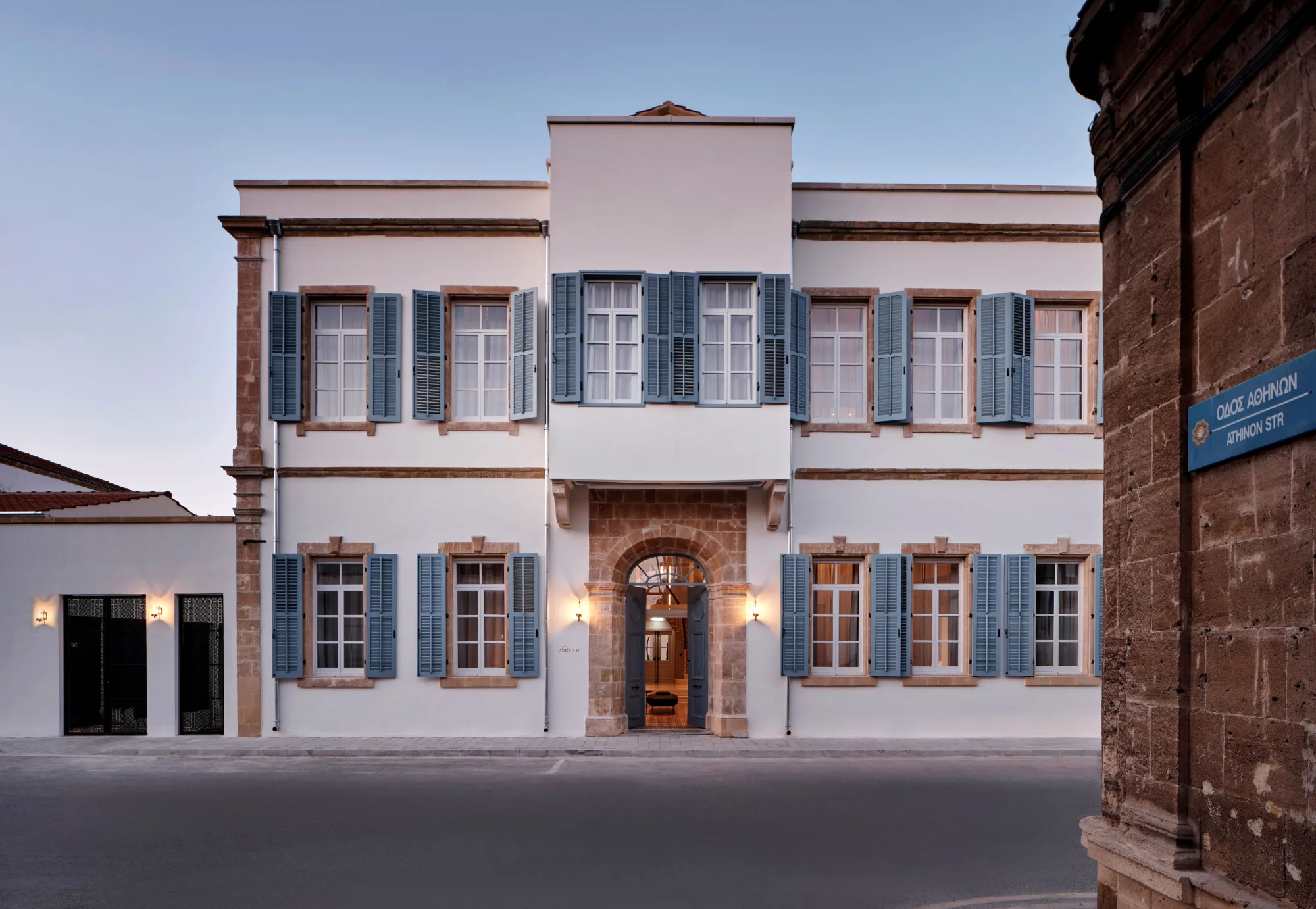 Historisches zweistöckiges Gebäude mit weißen Wänden und blauen Fensterläden in Nikosia bei Abendlicht.